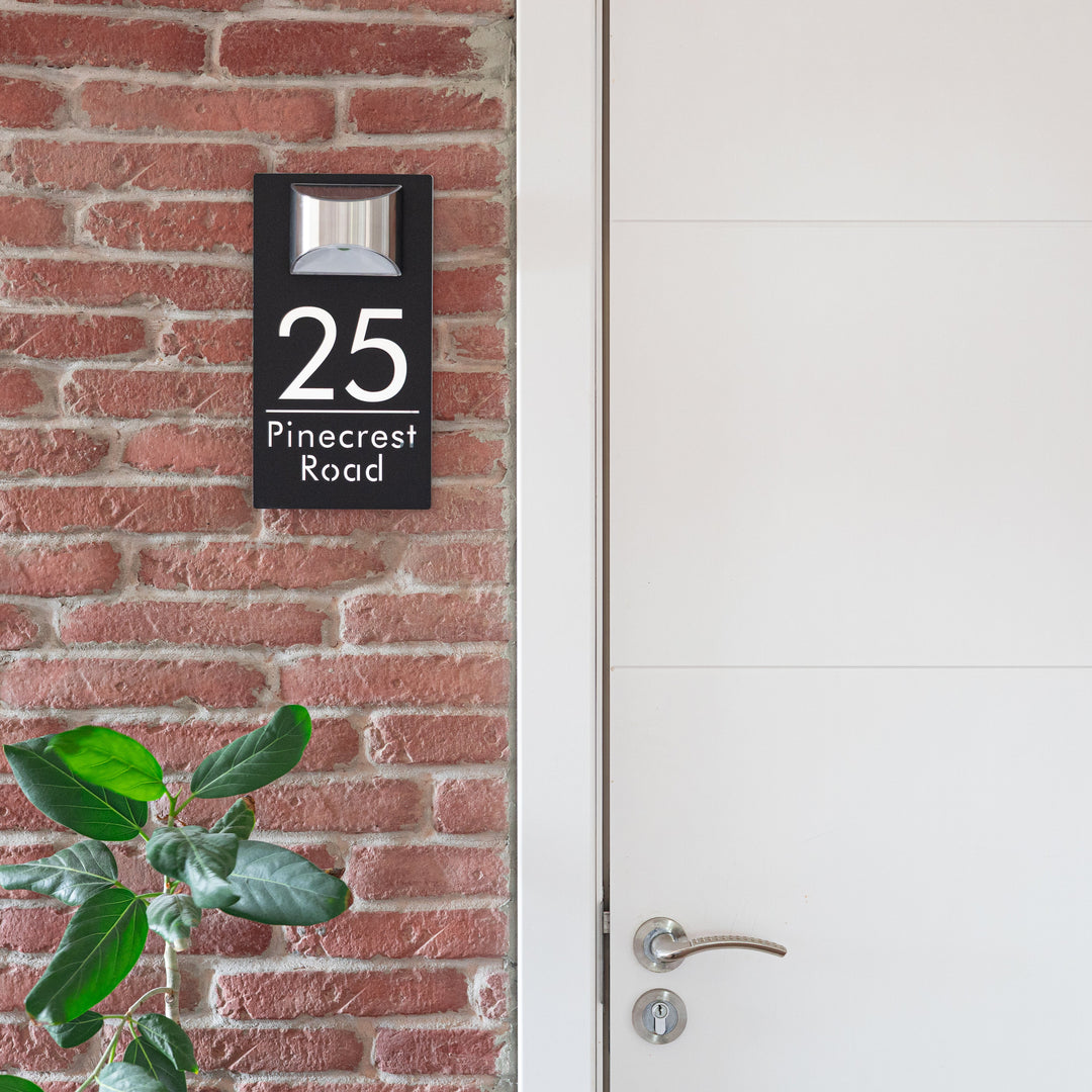 House number sign on a brick wall next to a white door