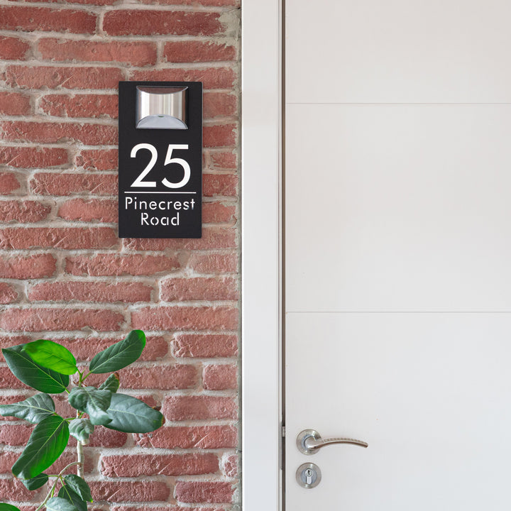 House number sign on a brick wall next to a white door