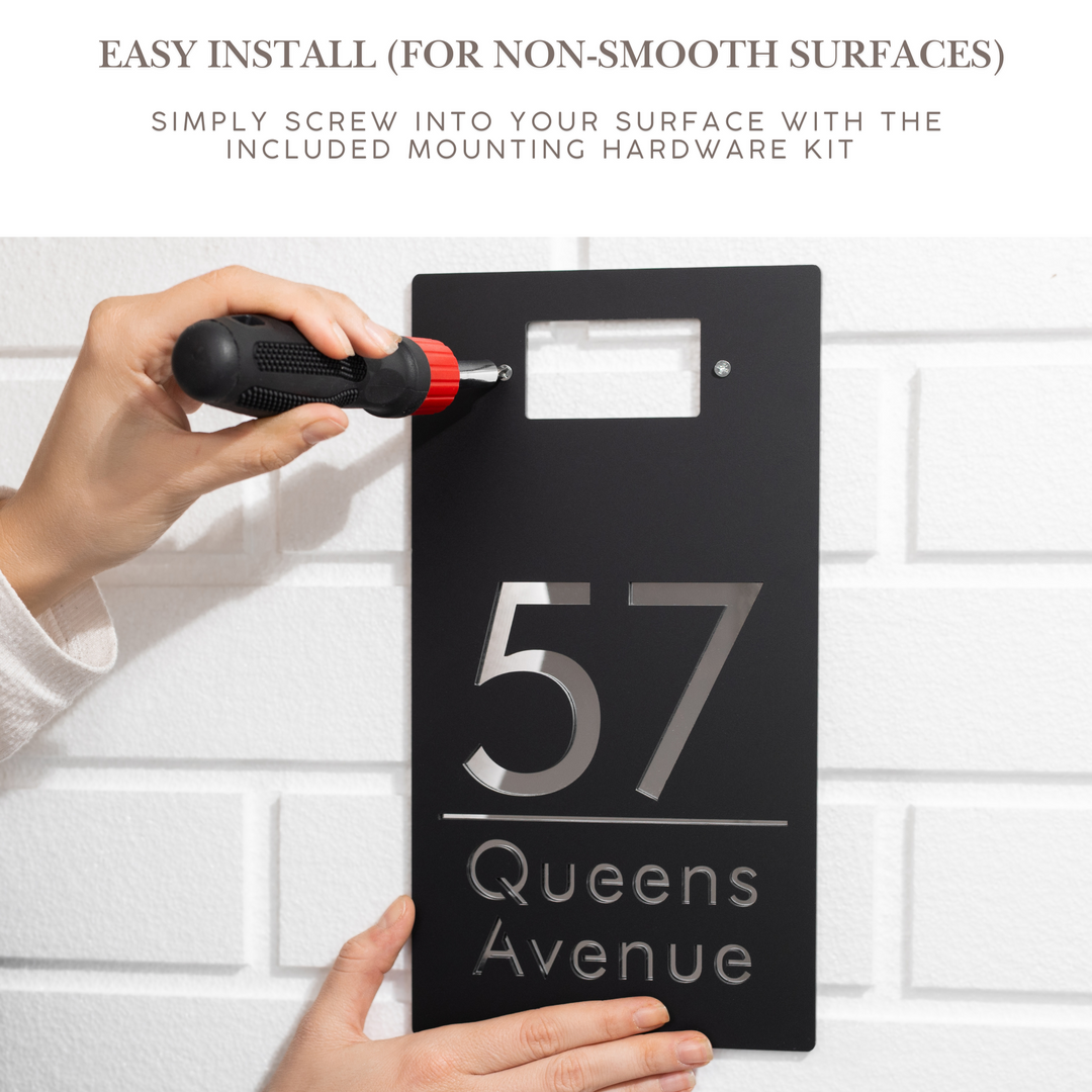 Person installing a black house number sign with &