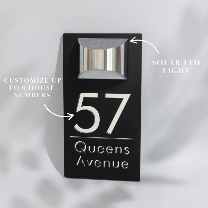 Black house number sign with solar LED light on a gray background
