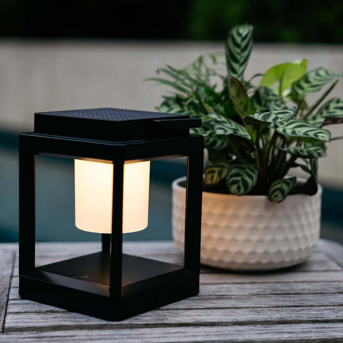 Solar table lantern glowing on an outdoor dining table after sunset