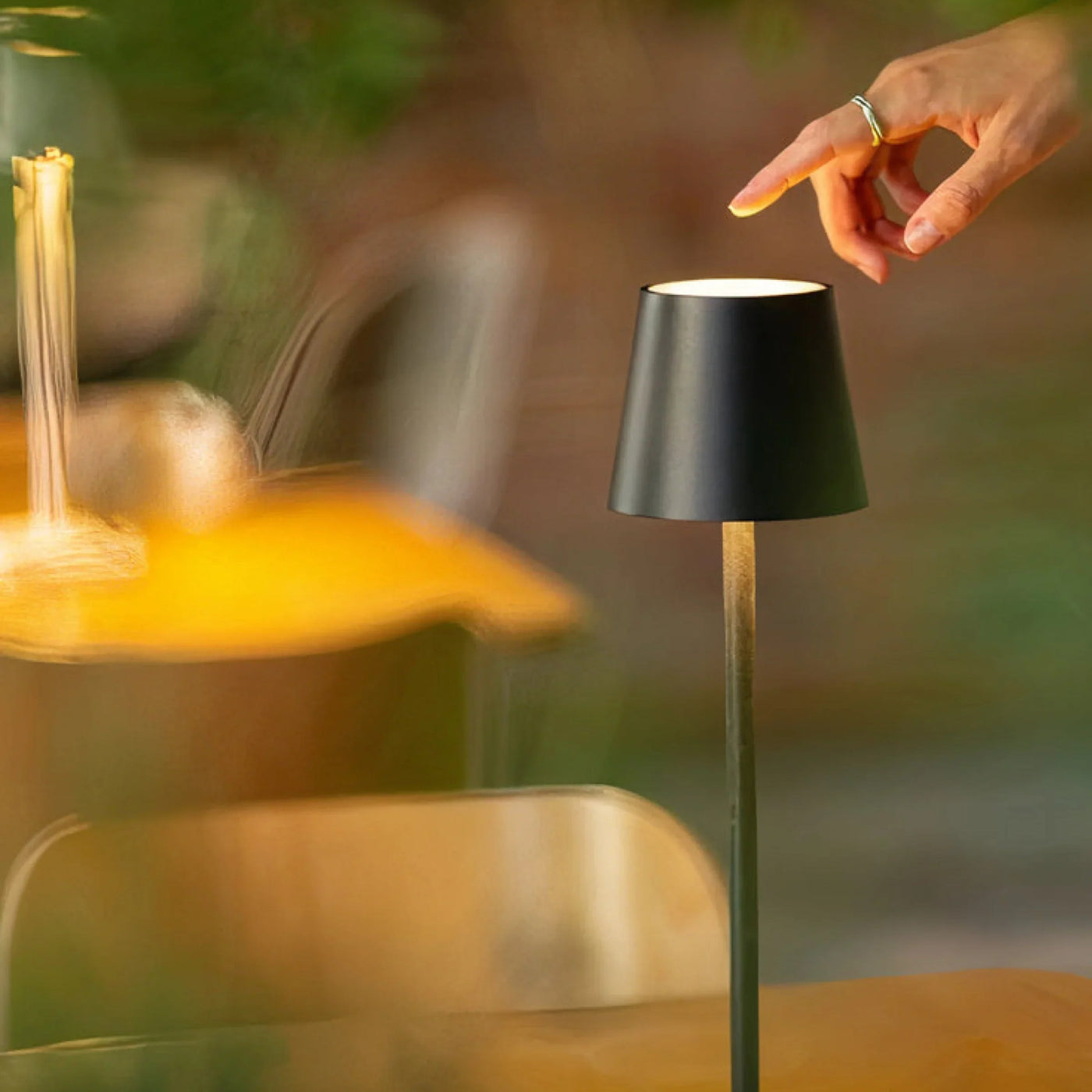 Cordless table lamp glowing amber on a bedside table at night