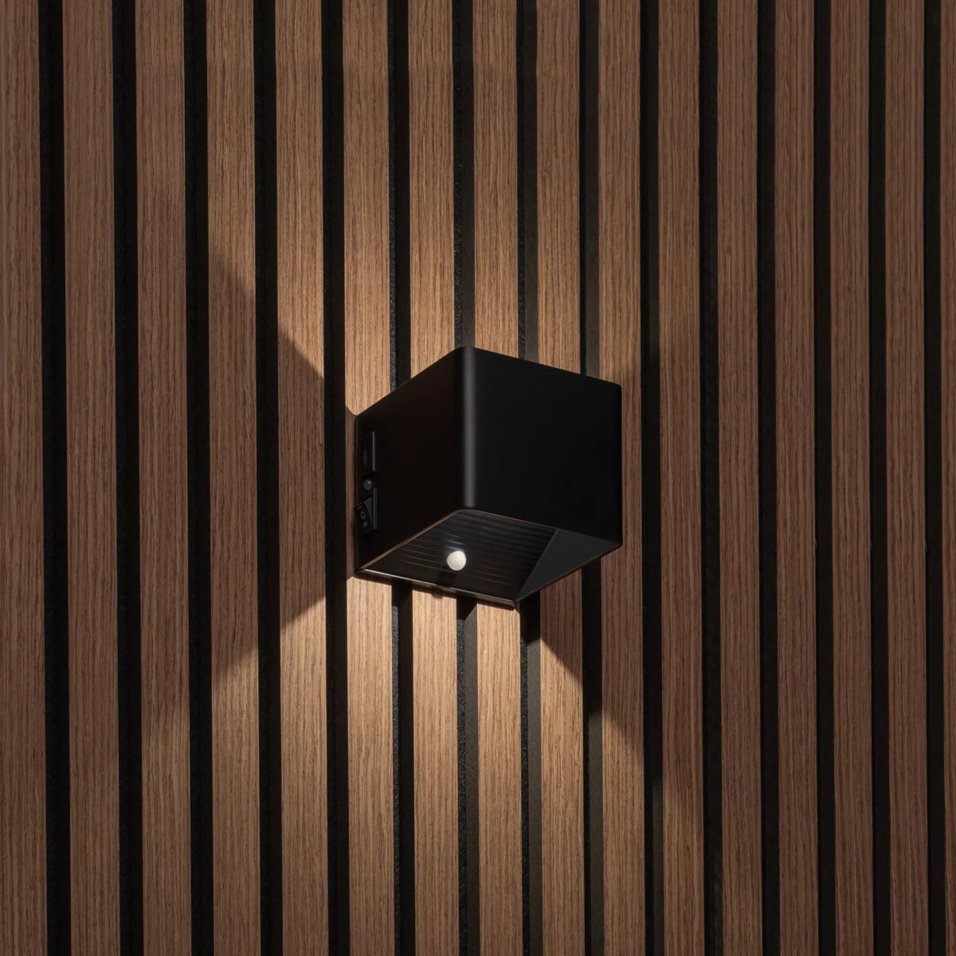 Motion sensor on a cordless wall lamp detecting movement in a hallway