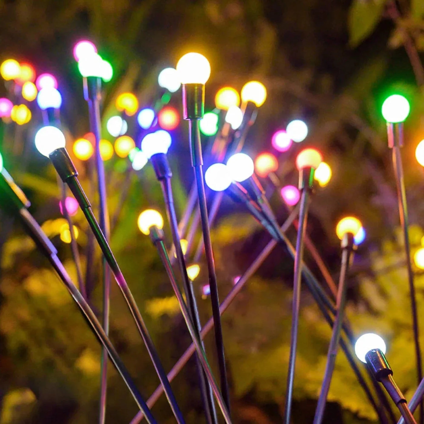 Ground stake of a solar firefly light being pushed into a garden bed