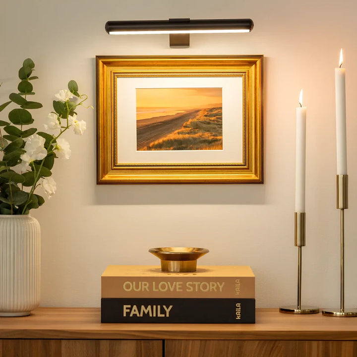 Decorative setup with framed artwork, books, and candles on a shelf.