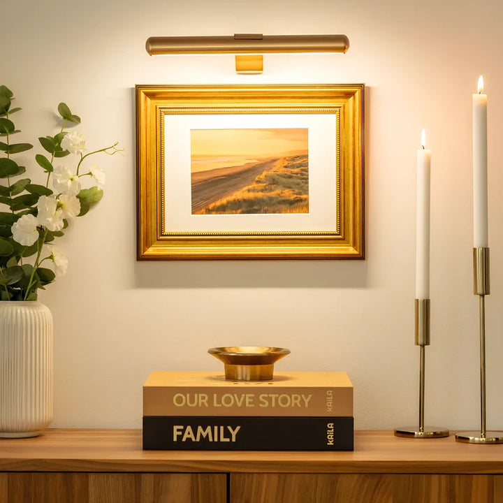 Decorative setup with a framed picture, books, and candles on a shelf.