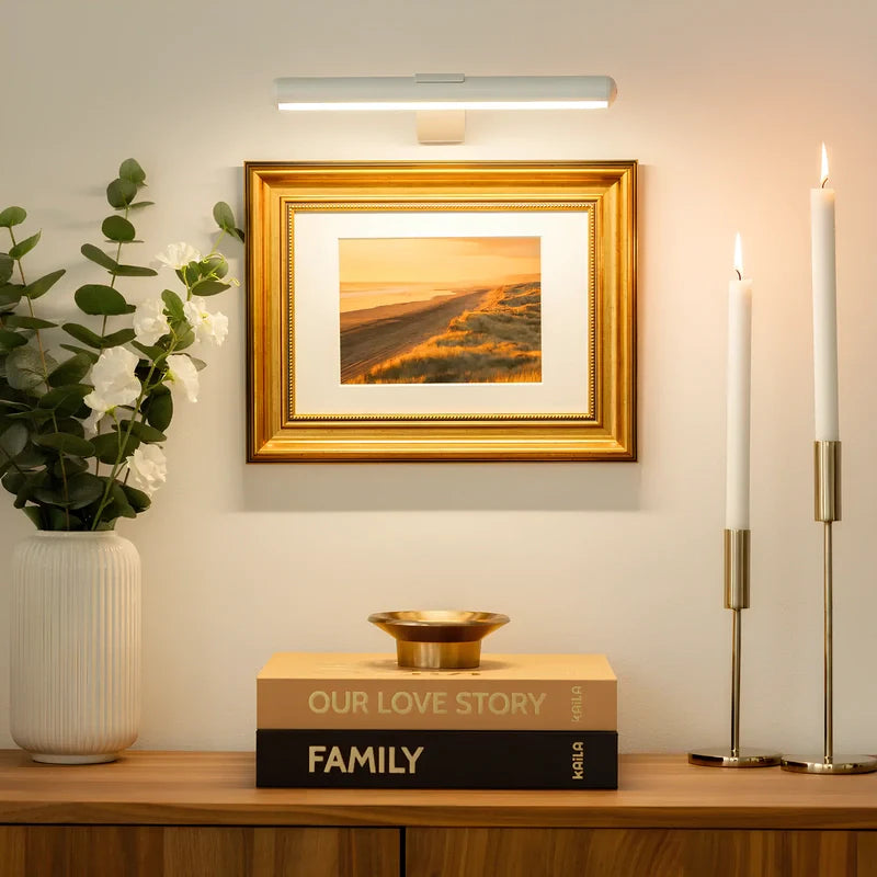 Decorative setup with a framed picture, candles, and books on a shelf.